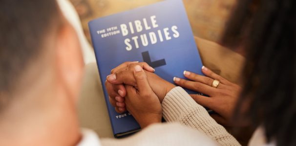 Religion, studying and couple holding hands with a bible for worship, prayer and trust in relations